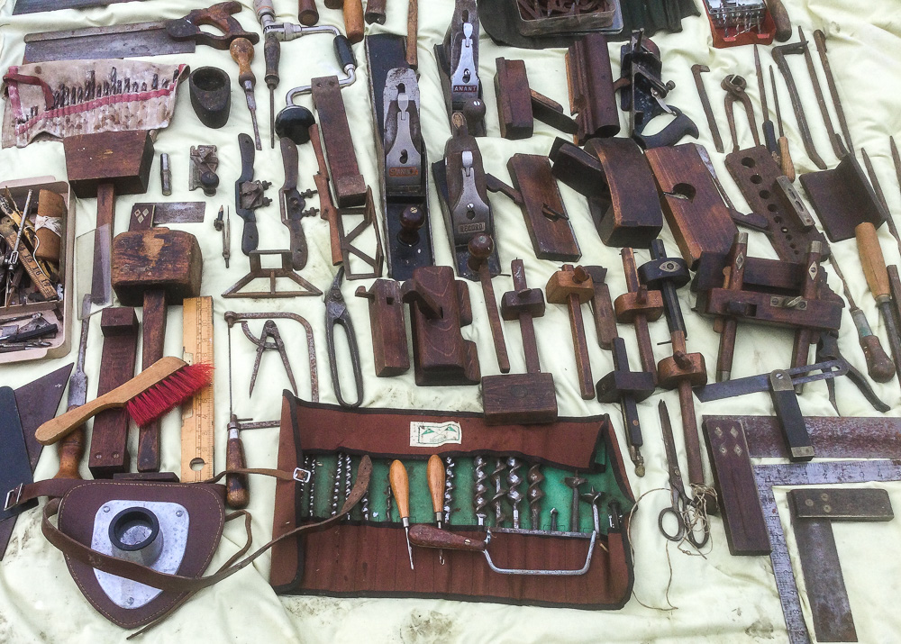 Vintage wood working tools laid out on an old sheet on the ground.